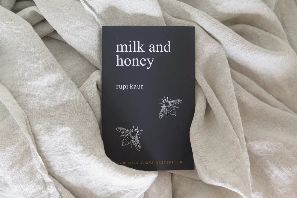 Paperback of Milk and Honey by Rupi Kaur on beige fabric.