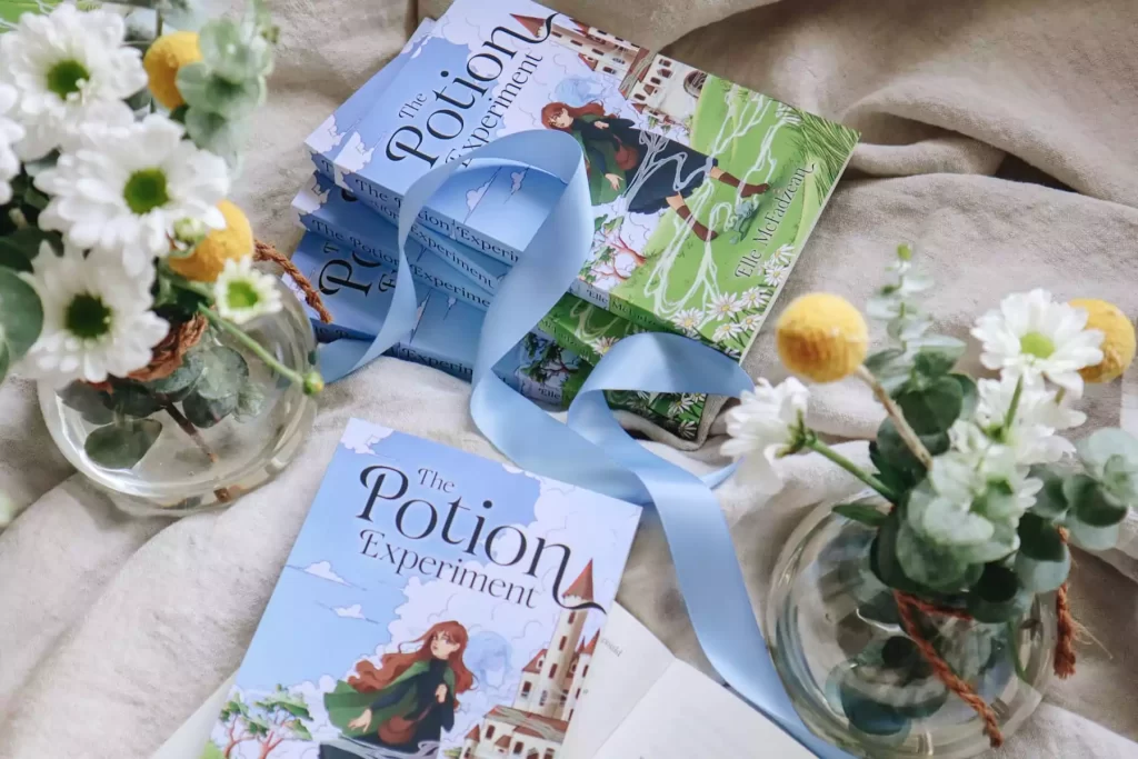 The Potion Experiment books surrounded by flowers and blue ribbon for a literary festival